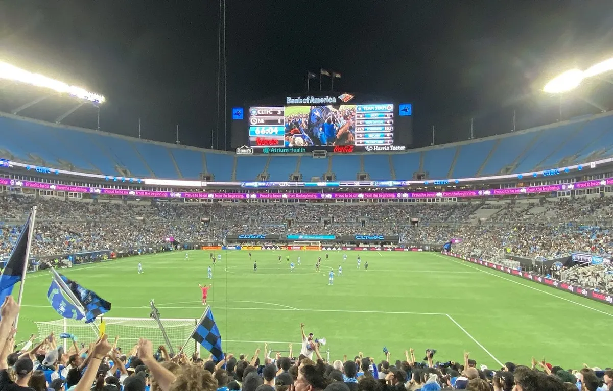 Charlotte FC fans in the supporters' section at Bank of America Stadium during a night MLS match against New England Revolution