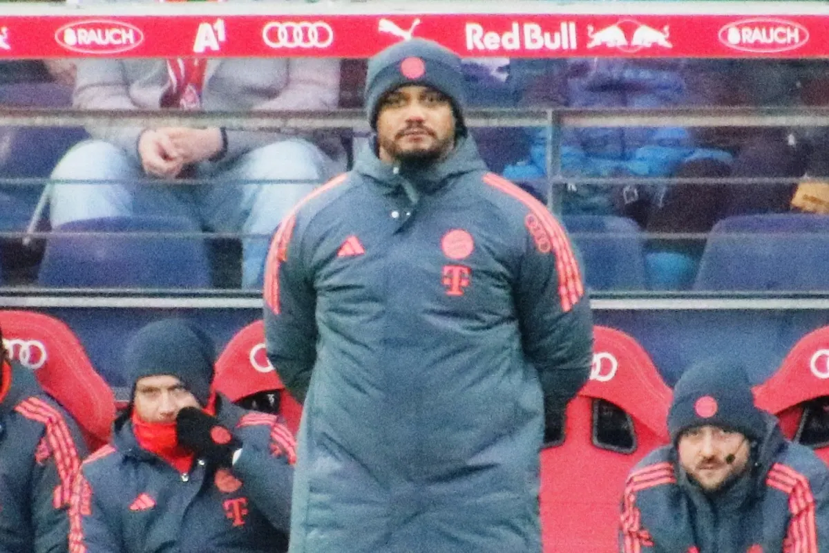 Bayern Munich head coach Vincent Kompany standing on the touchline in a club winter coat and hat, with Bayern staff on the bench behind him, at a friendly in Salzburg in January 2026