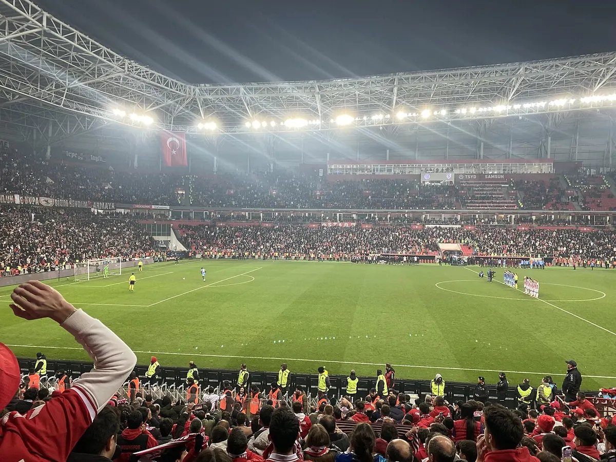 Paul Onuachu steps up to take a penalty in the shoot-out of Samsunspor v Trabzonspor in April 2026, seen from the home end of a packed, floodlit Samsun stadium with the other players lined up in the centre circle