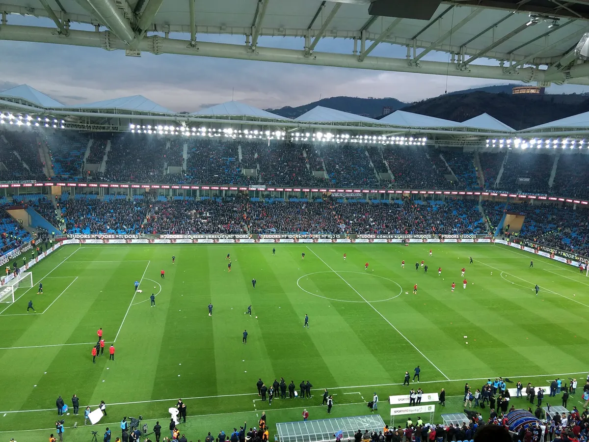 Floodlit Trabzon stadium full of Trabzonspor fans as players warm up before a Süper Lig match