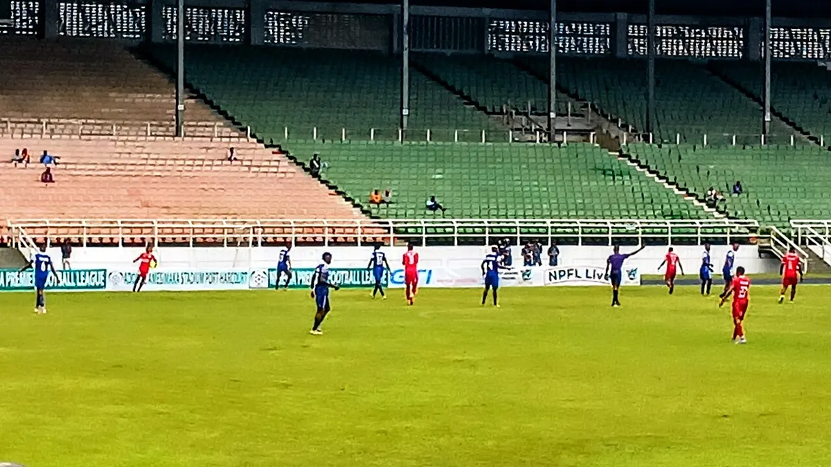 Rivers United players in blue and Katsina United players in red during an NPFL match at the Adokiye Amiesimaka Stadium in Port Harcourt, with green stands behind