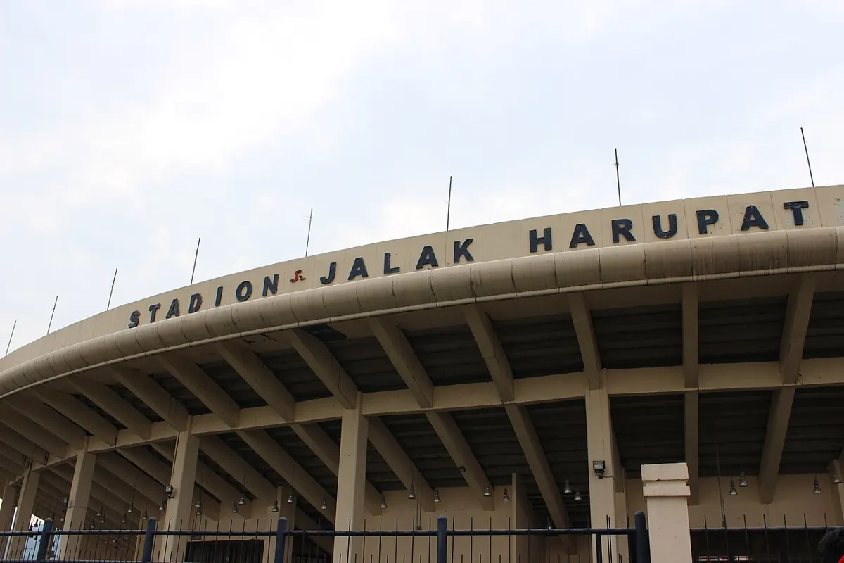 The curved roof and lettered facade of the Si Jalak Harupat Stadium in Soreang, Bandung Regency, Persib Bandung's home ground, under a pale sky