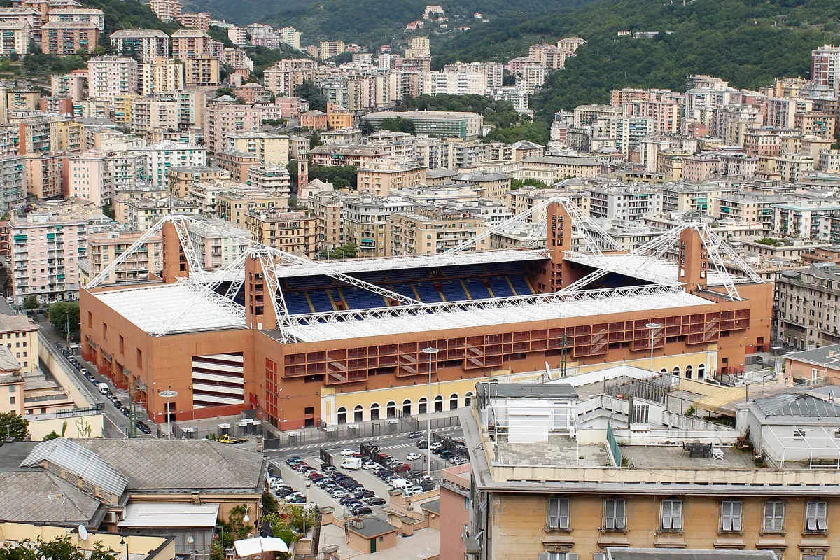 The Stadio Luigi Ferraris in Genoa, home of Genoa CFC, seen from above with its red walls, white roof and blue seats among the city's apartment blocks